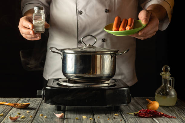 istock A skilled chef stands in a cozy kitchen, adding salt to a pot while holding a plate of sausages. Steam rises, creating an inviting atmosphere filled with culinary artistry 2195335078