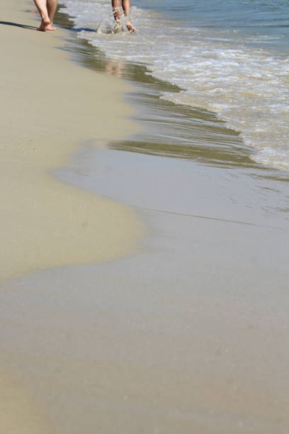 diverse couple walking along the water edge on a sandy beach of Skiathos island