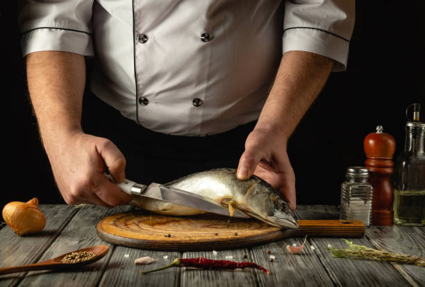 istock In a rustic kitchen, a skilled chef expertly slices fresh fish on a wooden cutting board, showcasing precision and artistry. The ingredients are artfully arranged, enhancing the culinary atmosphere 2195335502