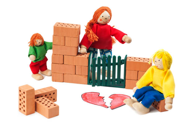 Still life with small dolls depicting the separation of a young family during house building with small clay pieces and broken ones on a white background.