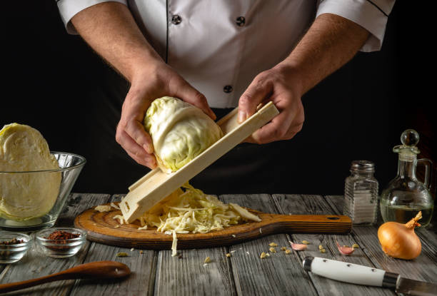 istock Under the warm glow of evening light, a skilled chef delicately shreds fresh cabbage using a mandoline. The kitchen exudes a cozy ambiance filled with culinary potential and creativity 2195335779