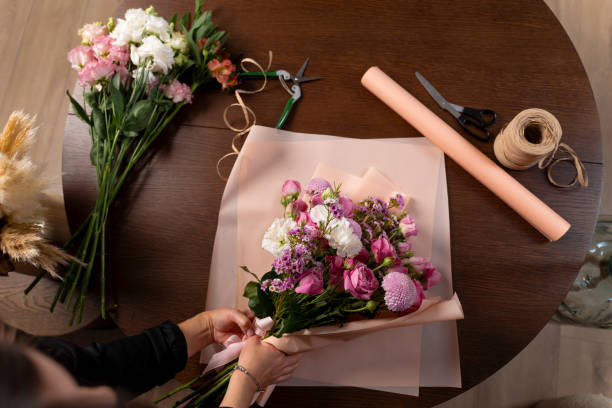 istock Collecting bouquet from carnations and roses, top view. Florist making a bouquet composition from flowers on the wooden table background. 2195337738