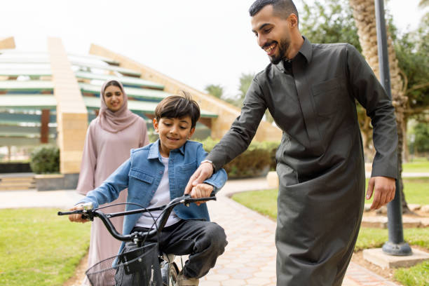 istock Middle Eastern father supporting son cycling at park 2195339530