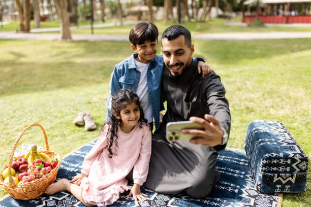 istock Happy Saudi man taking selfie with kids at park 2195339555