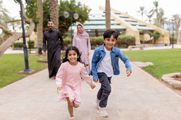 istock Happy children running with parents walking behind at park 2195339568