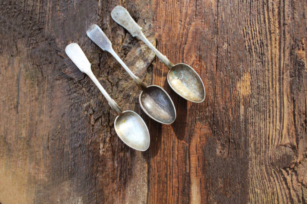 istock Old silver spoon that is dark from corrosion on wooden background 2195339916