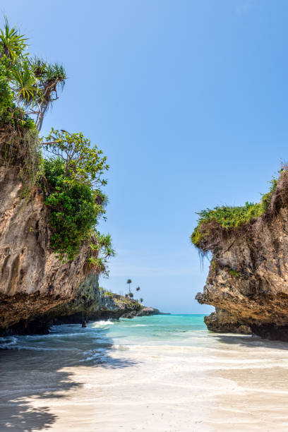 istock Turquoise waters washing pristine white sands, framed by rugged rocky cliffs and verdant greenery, revealing secluded tropical beauty of Mtende Beach in Zanzibar 2195345580