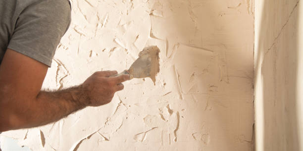 istock Man is applying putty on a wall. Renovating house 2195350953