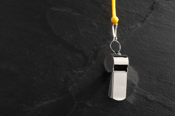 istock Referee equipment. Metal whistle on black textured background, closeup and space for text 2195351864