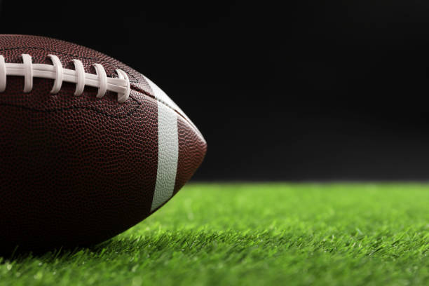 istock Rugby ball on green grass against black background, closeup. Space for text 2195351976