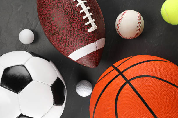 Many different sports balls on dark gray background, flat lay