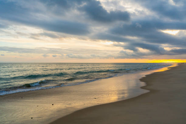 istock Glowing sunset over a quiet beach with gentle waves and a dramatic sky 2195352413