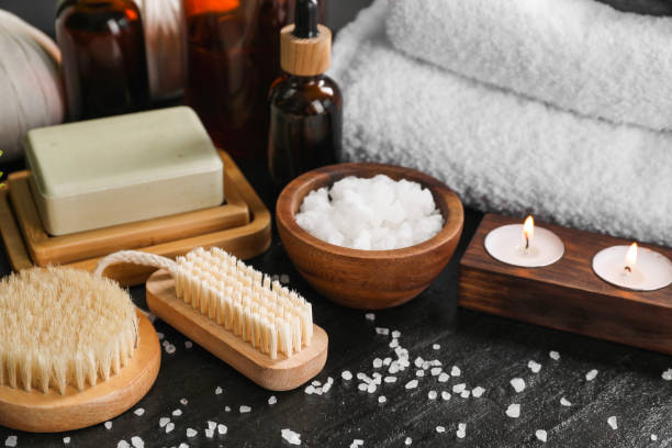 istock Spa composition. Brushes, soap bar, sea salt and burning candles on black table 2195353919