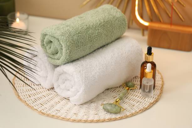 istock Spa composition. Rolled towels, cosmetic products and face roller on table 2195354628