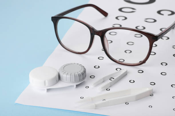 istock Vision test chart, glasses, lenses and tweezers on light blue background, closeup 2195355463