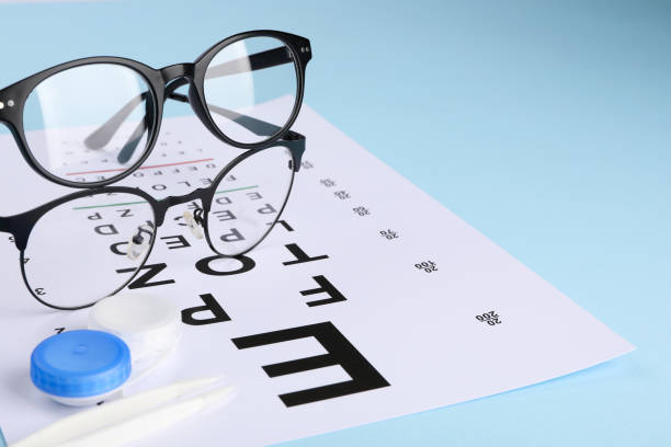 istock Vision test chart, glasses, lenses and tweezers on light blue background, closeup 2195355478