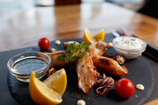 istock Grilled Squid with Lemon and Dipping Sauces on Slate Plate 2195355632