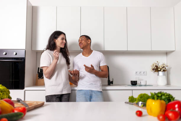 istock young multiracial couple standing in white modern kitchen with groceries and vegetables and talking 2195358043
