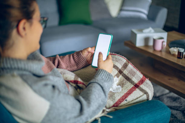 istock Sick woman resting on sofa at home and using smart phone 2195358673