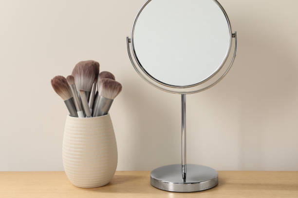 istock Mirror and makeup brushes on wooden dressing table in room 2195359348
