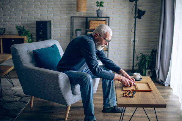 istock Senior man arranges chess pieces on a board and prepares for a solo chess game 2195360784