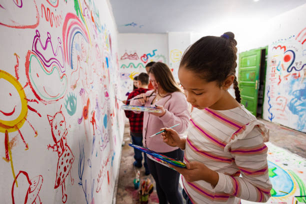 A collaborative art session where children paint a playful and colorful classroom mural.