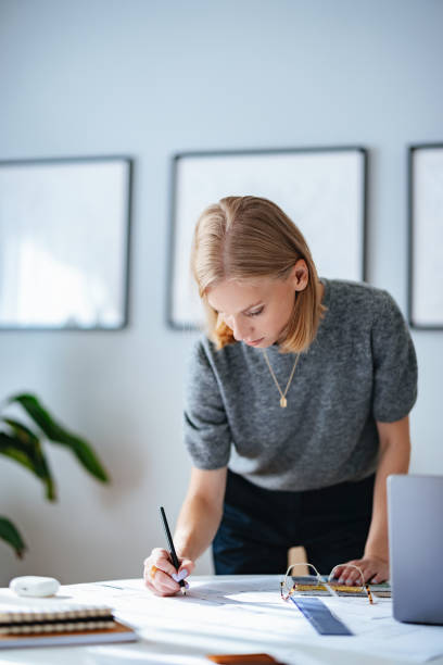 istock Focused Businesswoman Working on Design Plans in Modern Office 2195365574
