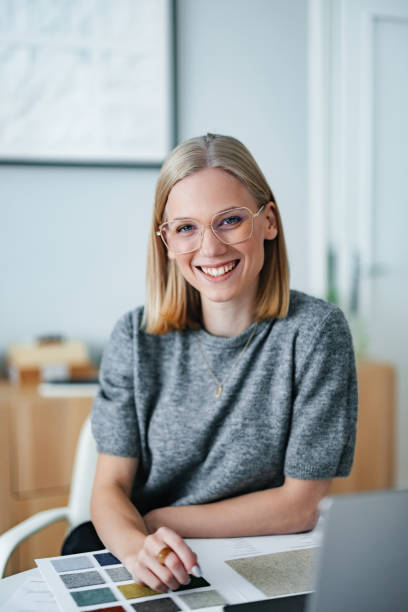 Young Businesswoman in Design Studio Reviewing Material Samples and Smiling