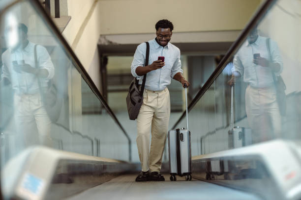 istock Man traveling  on the escalator with luggage using phone on public station 2195370201