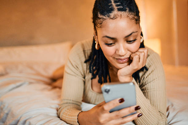 istock Woman with hand on chin using smart phone lying on bed 2195370534