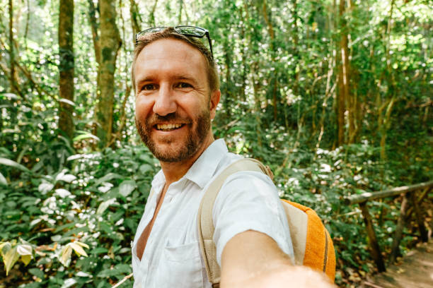 istock Adventurous man hiking in lush green forest with backpack 2195373490