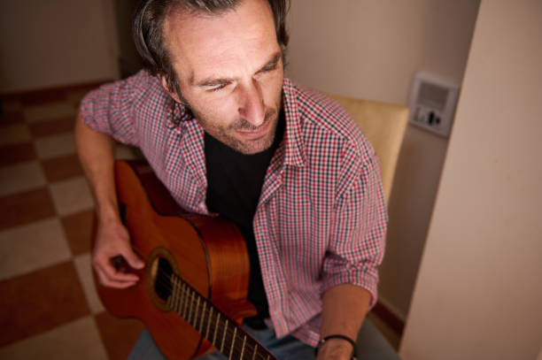 istock Man sitting playing acoustic guitar in a cozy indoor setting 2195390466