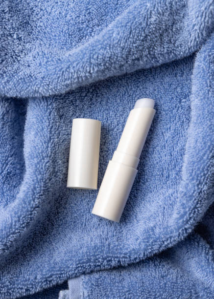 istock Opened white lip balm stick with a blank lid on blue bath towel top view, cosmetic mockup 2195392139