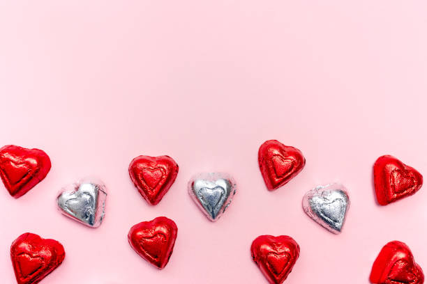 istock Colorful heart-shaped chocolates arranged in a playful pattern on a pink background 2195392313