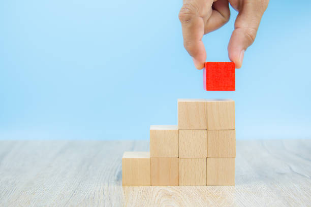 istock Close-up hand choose a red cube shape wooden block toy stacked in triangle shape without graphics for Business design concept and activity for child foundation practice skills 2195397020