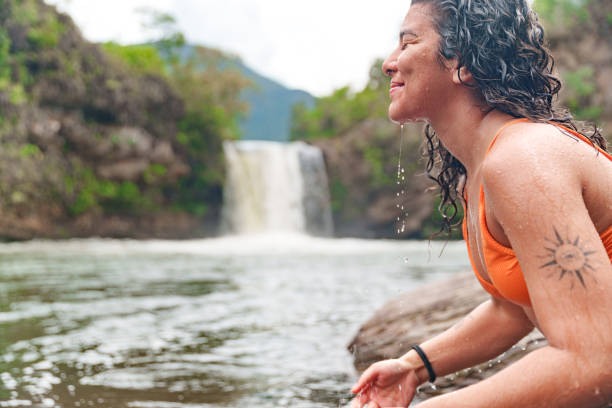 istock Young woman refreshing at waterfall 2195399182