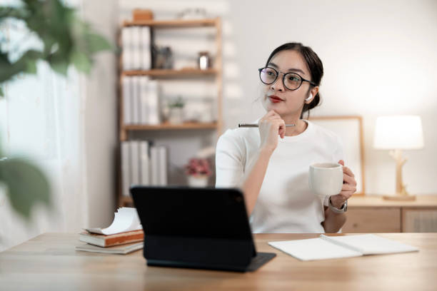 istock happy woman freelancer holding cup while using laptop at home 2195404151
