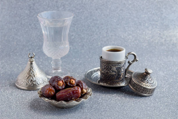 Traditional Arabian Bitter Coffee and dried date fruits on the shiny silver background.Ramadan Concept.