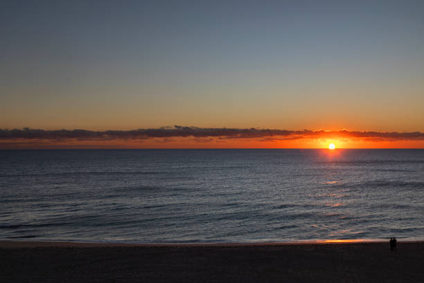 High angle view of a couple standing by the shore looking the sunrise at Lauderdale By The Sea Beach, Fort Lauderdale, Florida, USA
