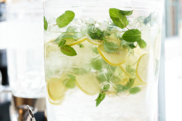 Refreshing Cold Lemon Mint Water in Glass Dispenser - Lemon slices and fresh mint in ice water.