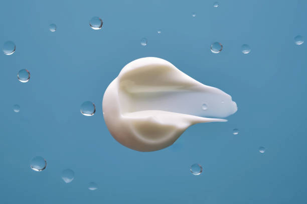 istock Swatch with white cream texture on a blue background with water drops. 2195406486