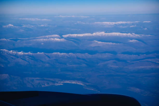 Aerial view of a snow-capped mountain range seen from an airplane window, offering a breathtaking perspective of nature's grandeur