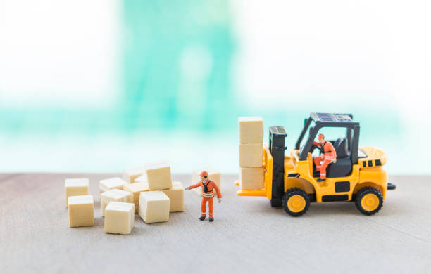 istock Miniature worker with forklift truck and wooden cube over blurred background 2195412272