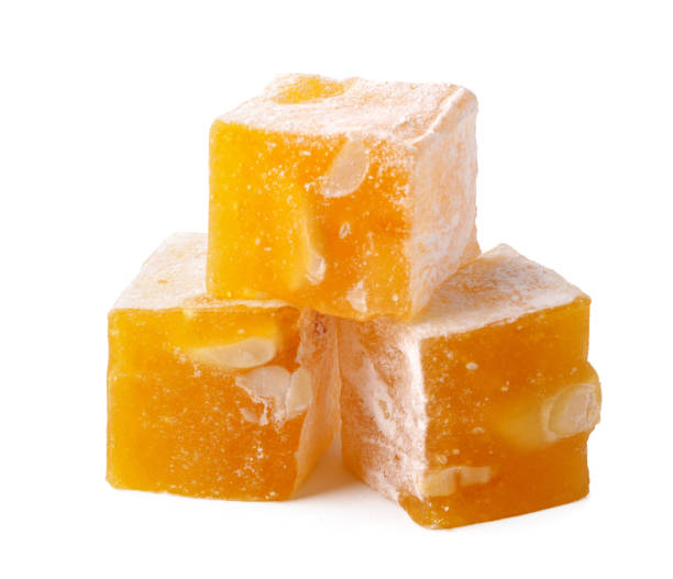 istock Delicious yellow candy squares with nuts stacked on a white surface 2195412305