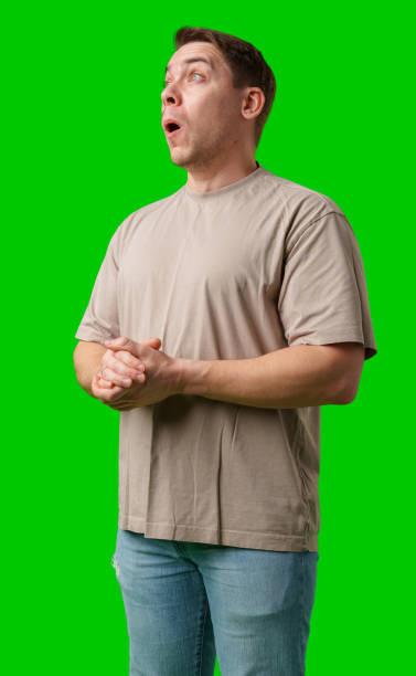istock A surprised man stands in front of a bright green screen, expressing shock with his mouth open 2195413528