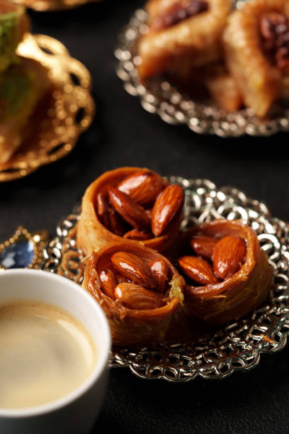 Delicate pastries filled with nuts are beautifully arranged on ornate plates beside a steaming cup of rich coffee, creating an inviting atmosphere for indulgence.