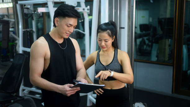istock Personal trainer and his client reviewing workout progress in the gym 2195415167