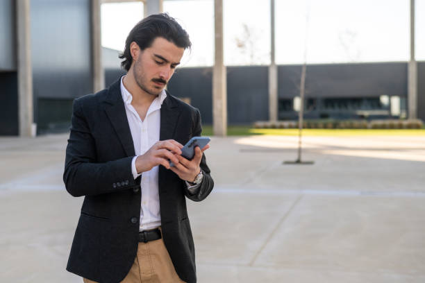 istock Successful Entrepreneur Checking Smartphone for Business Communication, Highlighting Online Work, Modern Connectivity, and Professional Dedication in a Stylish Setting. 2195416348