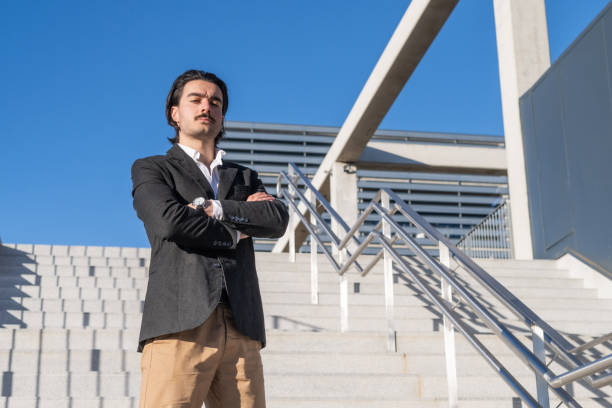 istock Confident Businessman Standing Outside Modern Office Tower, Wearing Elegant Suit , Successful Corporate Leader In Urban Business District, Daylight Scene 2195416593