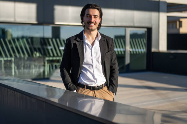 istock Cheerful And Confident Businessman Standing Outside Modern Office Architecture, Wearing Formal Business Suit, Smiling At Camera In Corporate Urban Environment 2195416732